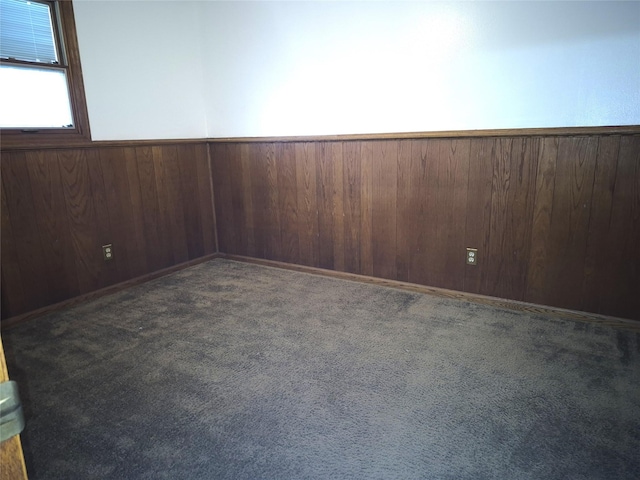 carpeted empty room featuring wooden walls