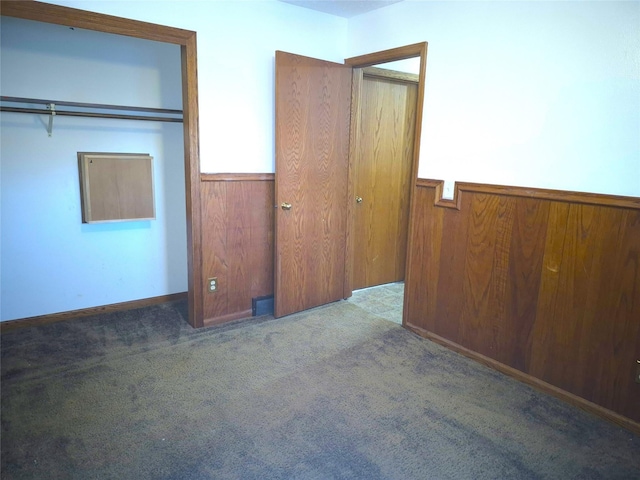 unfurnished bedroom featuring wooden walls and carpet flooring