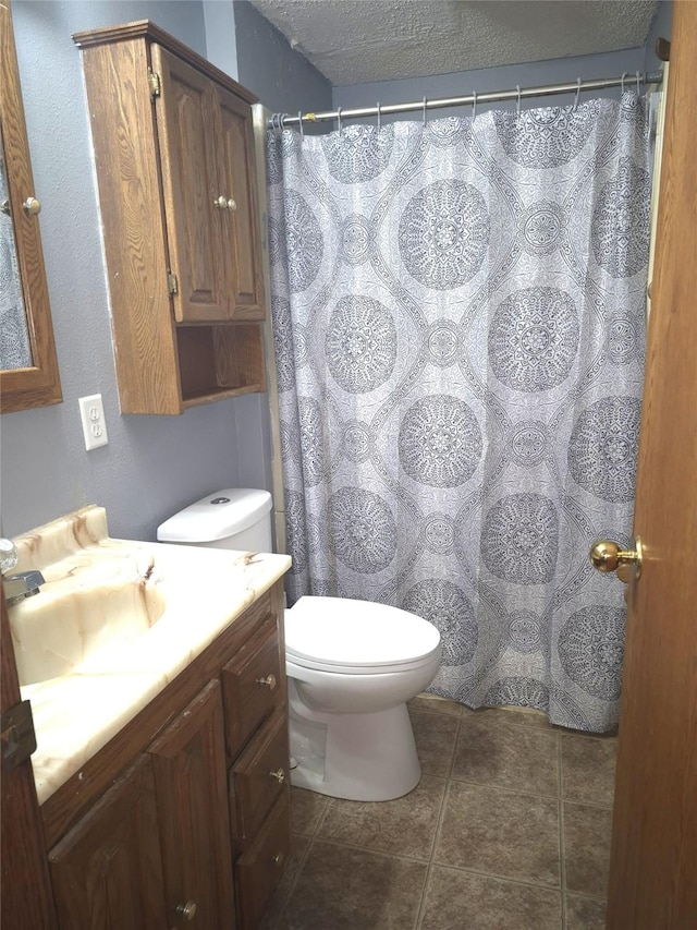 bathroom with vanity, a textured ceiling, tile patterned floors, and toilet