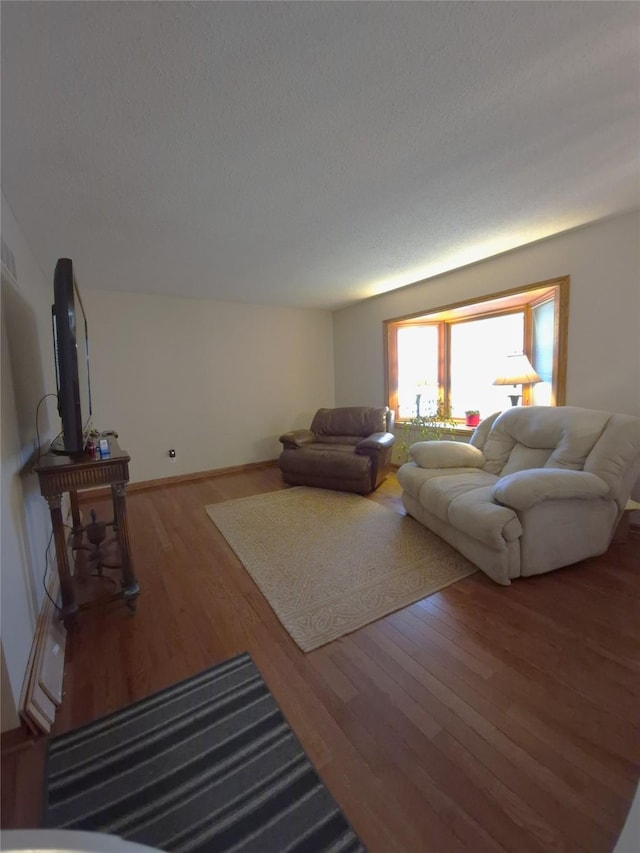 living room featuring hardwood / wood-style flooring, lofted ceiling, and a textured ceiling