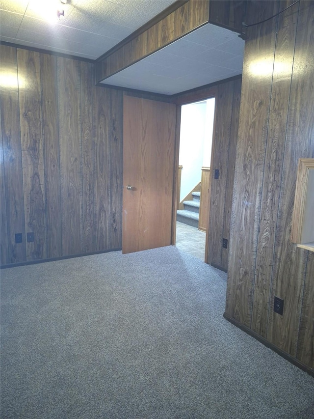 carpeted empty room with wood walls