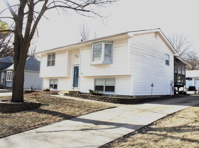 raised ranch with a garage, concrete driveway, and entry steps