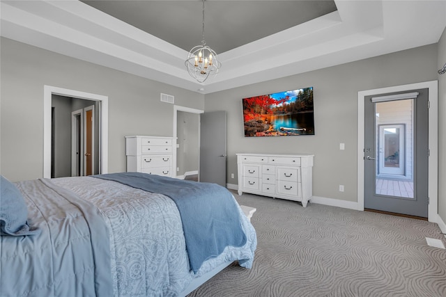 carpeted bedroom with a raised ceiling and an inviting chandelier