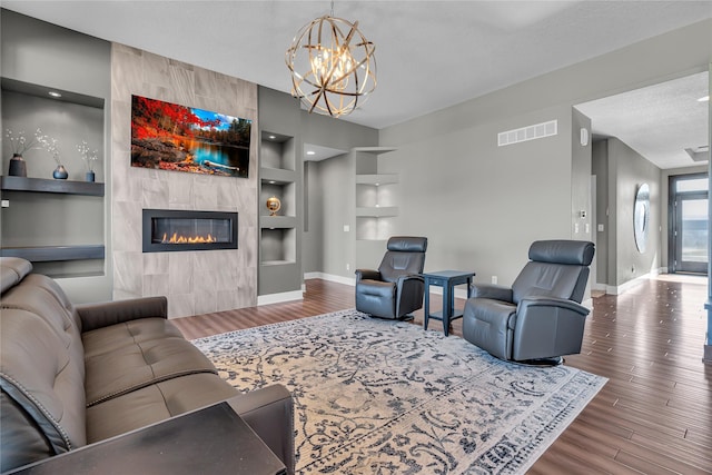 living room with built in shelves, a fireplace, hardwood / wood-style floors, and a textured ceiling