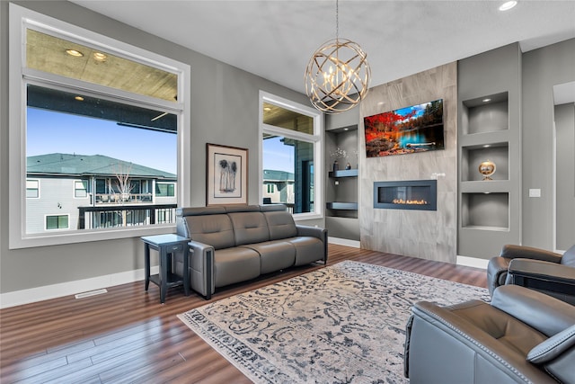 living room featuring dark hardwood / wood-style flooring, built in shelves, a fireplace, and a healthy amount of sunlight