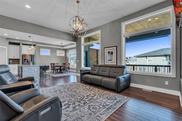 living room featuring dark wood-type flooring, a wealth of natural light, and a chandelier