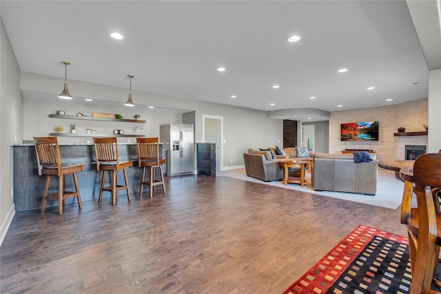 living room featuring indoor bar, wood-type flooring, and a large fireplace