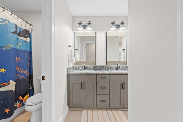 bathroom featuring double vanity, tile patterned flooring, toilet, and a sink