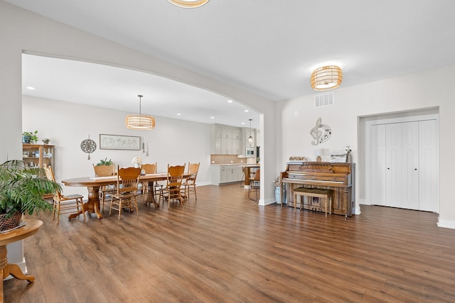 dining room featuring baseboards, visible vents, arched walkways, wood finished floors, and recessed lighting