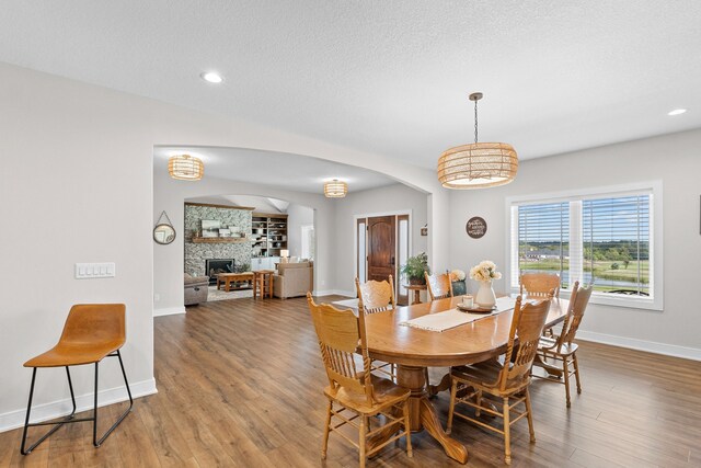 dining room featuring hardwood / wood-style flooring, a fireplace, and a textured ceiling