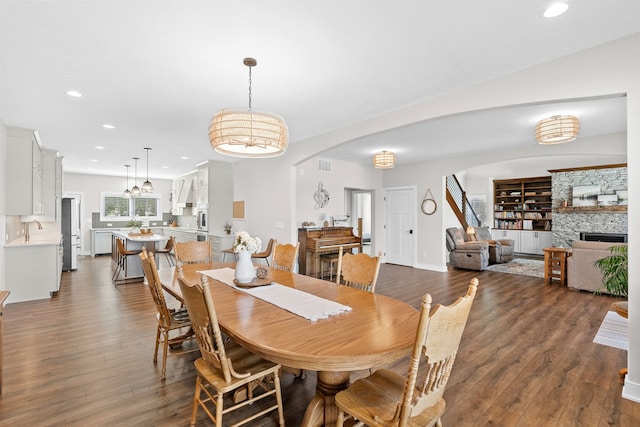 dining room featuring recessed lighting, visible vents, dark wood-type flooring, and a stone fireplace