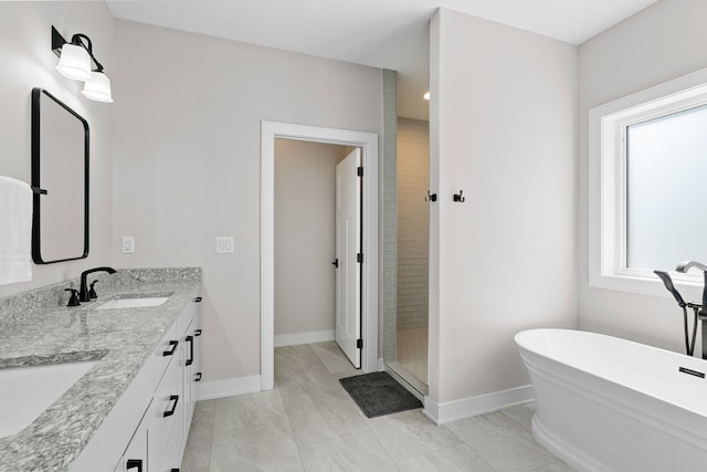 bathroom featuring baseboards, a freestanding tub, a sink, and a shower stall