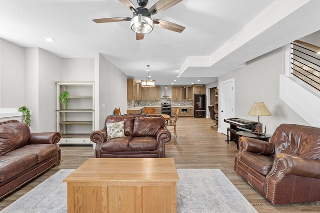 living area featuring light wood finished floors, stairway, a ceiling fan, and recessed lighting