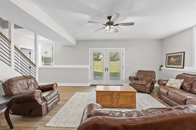 living area featuring light wood-style floors, french doors, ceiling fan, and stairs