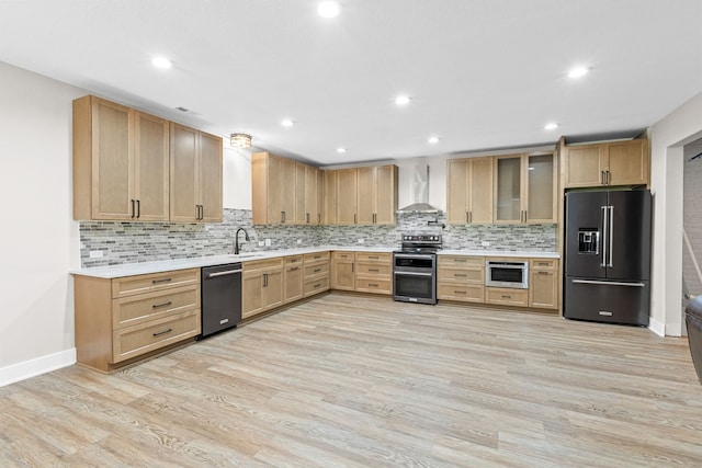 kitchen featuring dishwashing machine, range with two ovens, high end black refrigerator, a sink, and wall chimney range hood