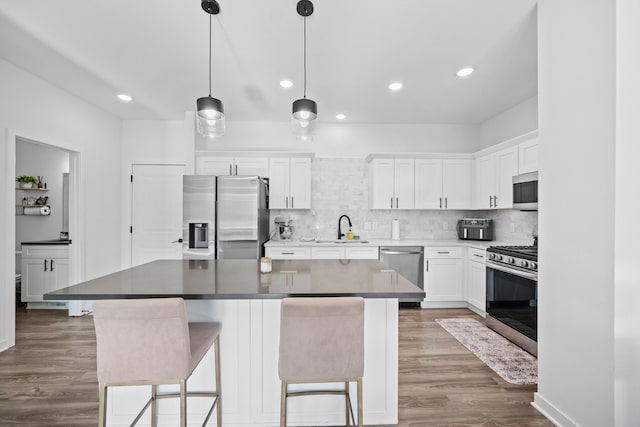 kitchen with tasteful backsplash, wood finished floors, stainless steel appliances, and a sink