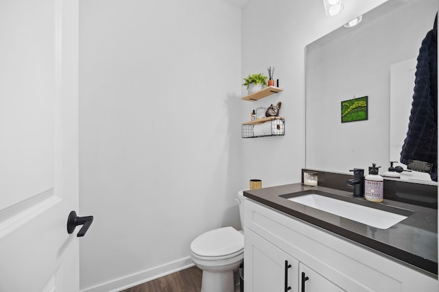 bathroom with vanity, toilet, wood finished floors, and baseboards