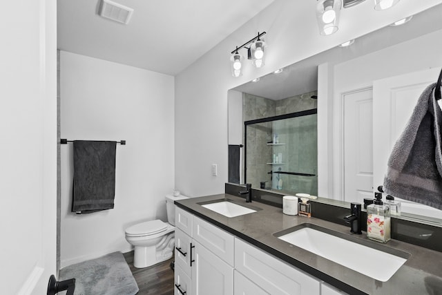 bathroom featuring vanity, wood-type flooring, a shower with shower door, and toilet