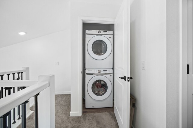 laundry room with stacked washer and dryer and dark carpet