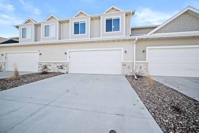 multi unit property featuring concrete driveway and stone siding