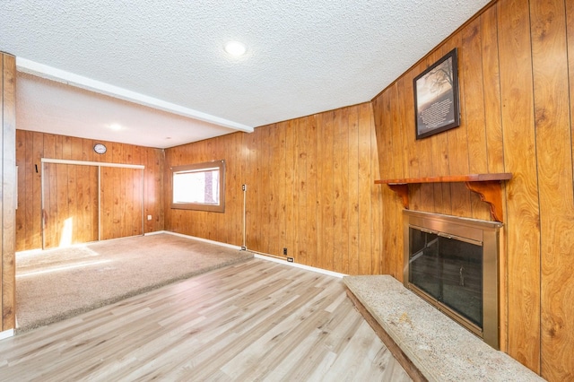 unfurnished living room with light hardwood / wood-style flooring, a textured ceiling, and wood walls