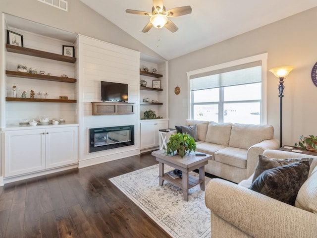 living room featuring lofted ceiling, built in shelves, dark wood-type flooring, and ceiling fan