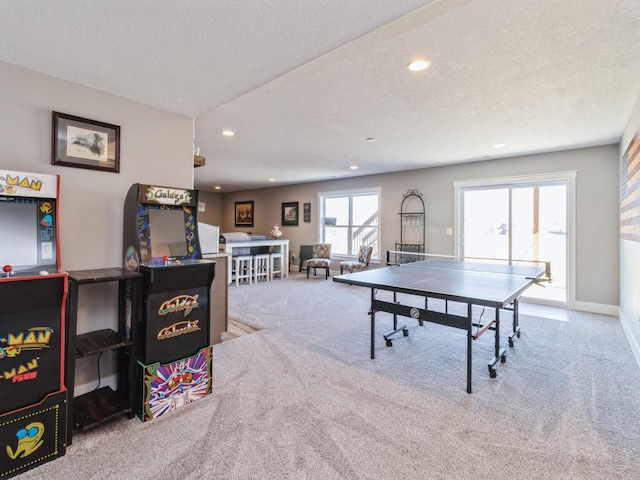 rec room featuring light colored carpet and a textured ceiling