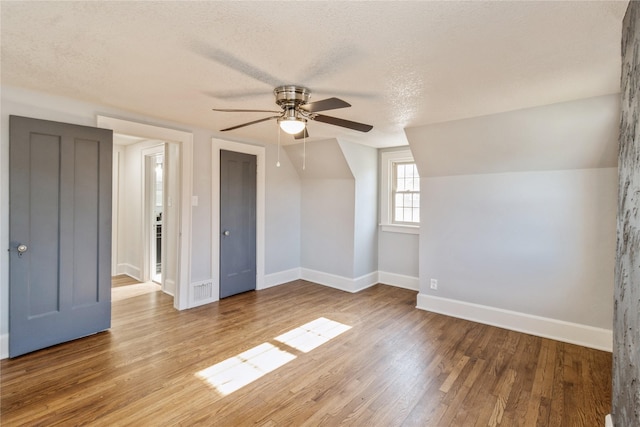 bonus room featuring hardwood / wood-style flooring, ceiling fan, lofted ceiling, and a textured ceiling