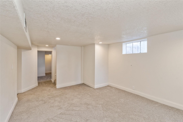 basement featuring light carpet and a textured ceiling