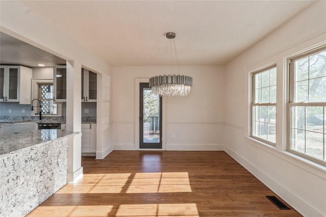 dining space featuring wood-type flooring, sink, and an inviting chandelier