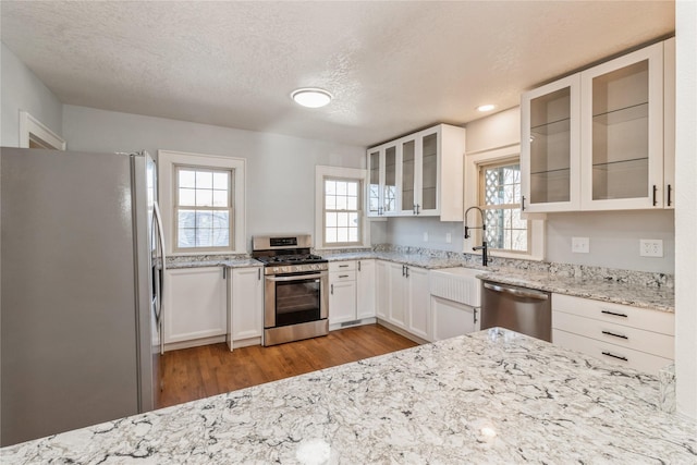 kitchen featuring sink, light stone counters, light wood-type flooring, stainless steel appliances, and white cabinets