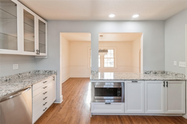 kitchen featuring stainless steel appliances, white cabinetry, light stone counters, and light hardwood / wood-style floors