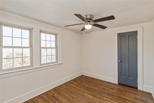 empty room featuring ceiling fan, dark wood-type flooring, and a textured ceiling