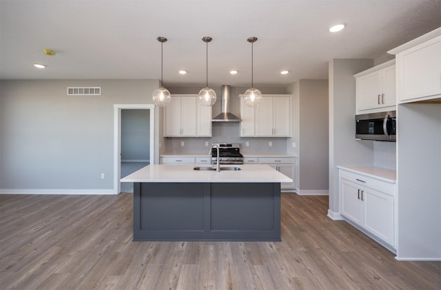 kitchen featuring white cabinetry, sink, wall chimney exhaust hood, and appliances with stainless steel finishes