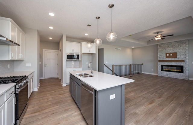 kitchen featuring pendant lighting, sink, white cabinetry, stainless steel appliances, and a center island with sink