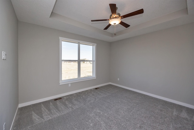 spare room featuring a tray ceiling, carpet floors, a textured ceiling, and ceiling fan