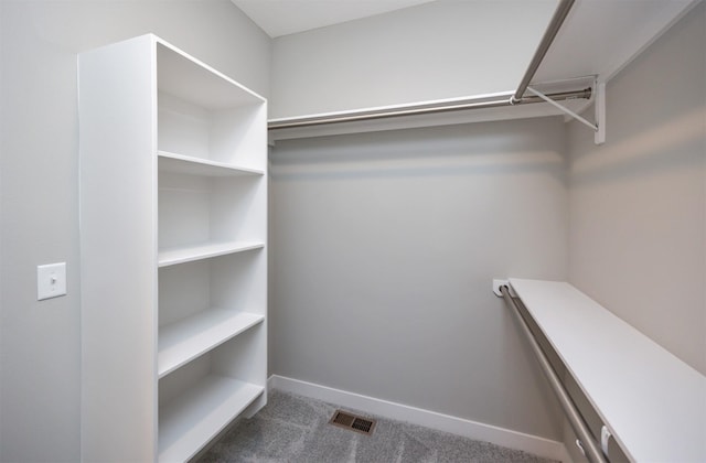 walk in closet featuring dark carpet