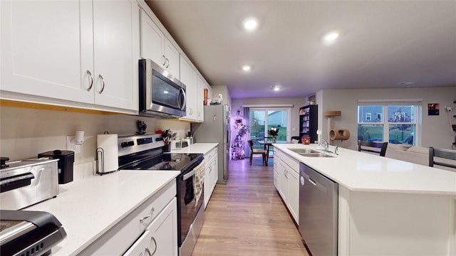 kitchen with stainless steel appliances, white cabinetry, and a kitchen island with sink