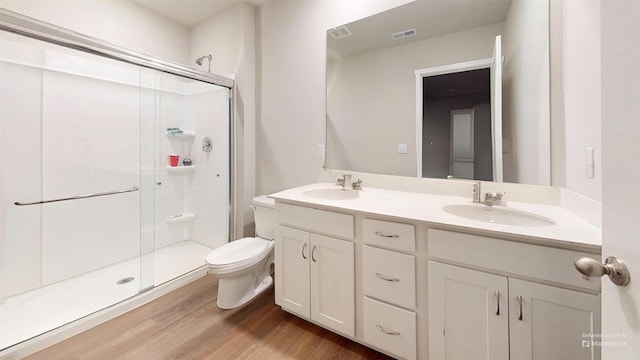 bathroom featuring hardwood / wood-style flooring, toilet, vanity, and a shower with shower door