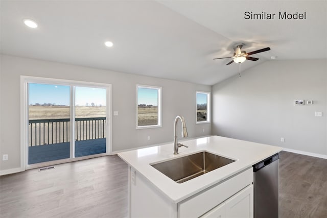 kitchen with sink, a kitchen island with sink, white cabinetry, vaulted ceiling, and stainless steel dishwasher