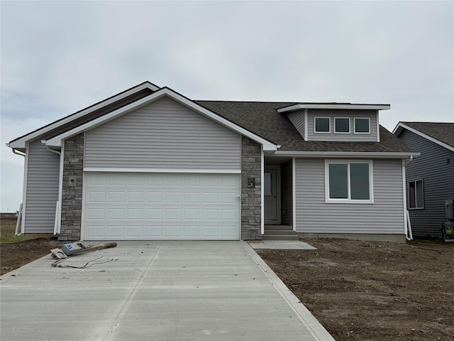 505 Fireside Dr NW, Bondurant, IA 50035 - view of front of house featuring stone siding, driveway, roof with shingles, and a garage
