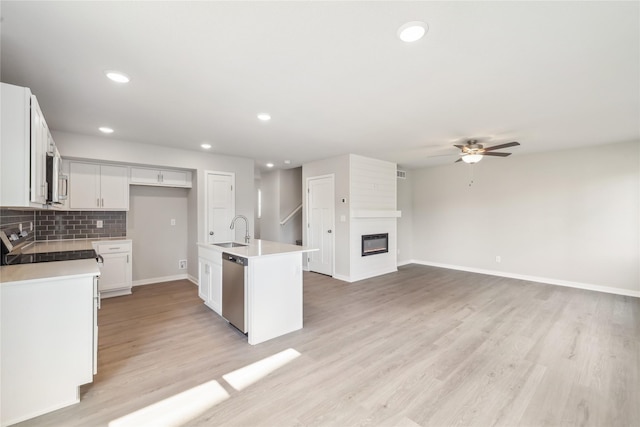 kitchen with stainless steel appliances, a sink, white cabinetry, ceiling fan, and light countertops