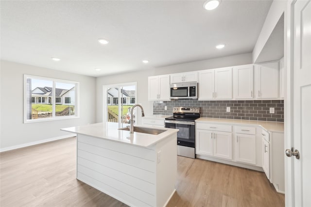kitchen featuring decorative backsplash, light wood-style flooring, stainless steel appliances, and a sink