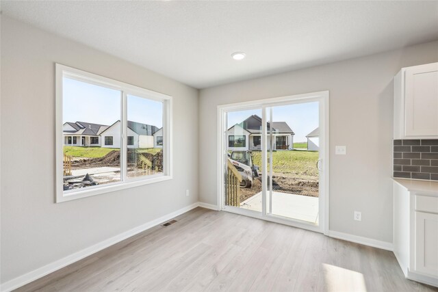 unfurnished dining area featuring baseboards, light wood finished floors, and plenty of natural light