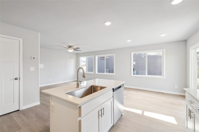 kitchen featuring open floor plan, dishwasher, a sink, and light wood-style flooring