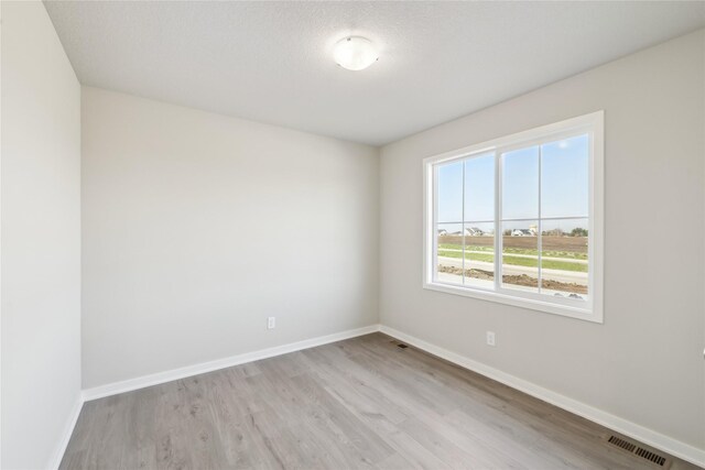 spare room featuring baseboards, light wood finished floors, and visible vents