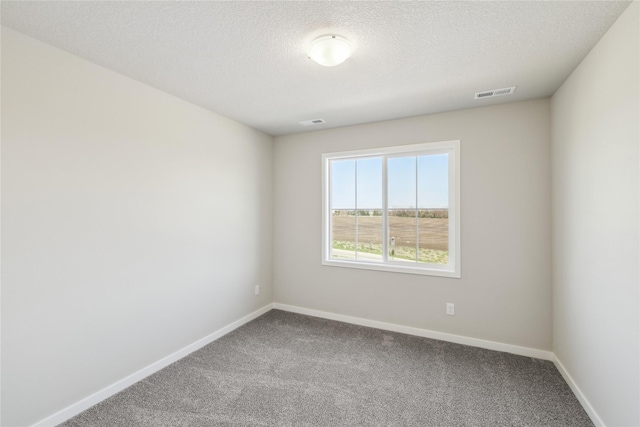 carpeted spare room with baseboards, a textured ceiling, and visible vents