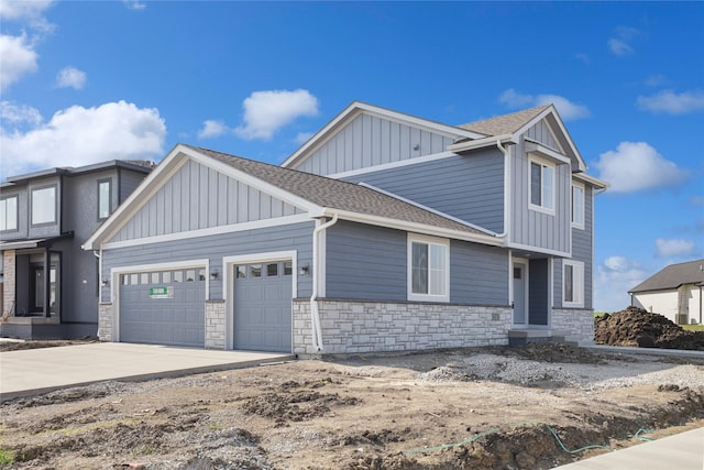 craftsman inspired home featuring driveway, stone siding, board and batten siding, a shingled roof, and an attached garage