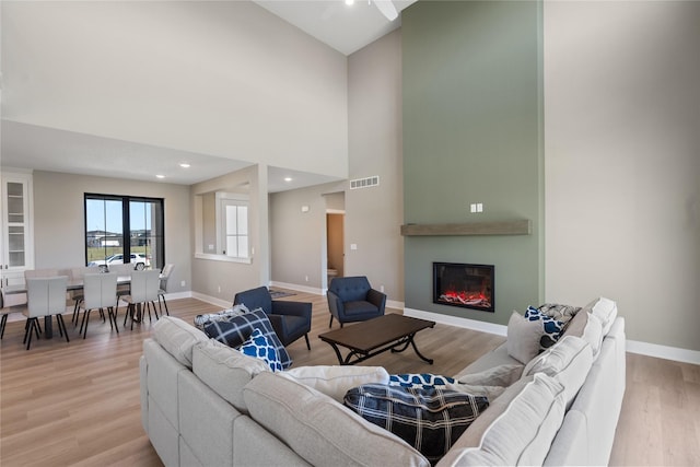 living room with a towering ceiling and light wood-type flooring