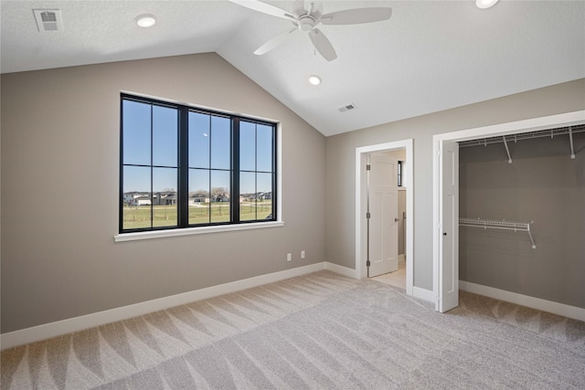 unfurnished bedroom with ceiling fan, a closet, vaulted ceiling, and light carpet